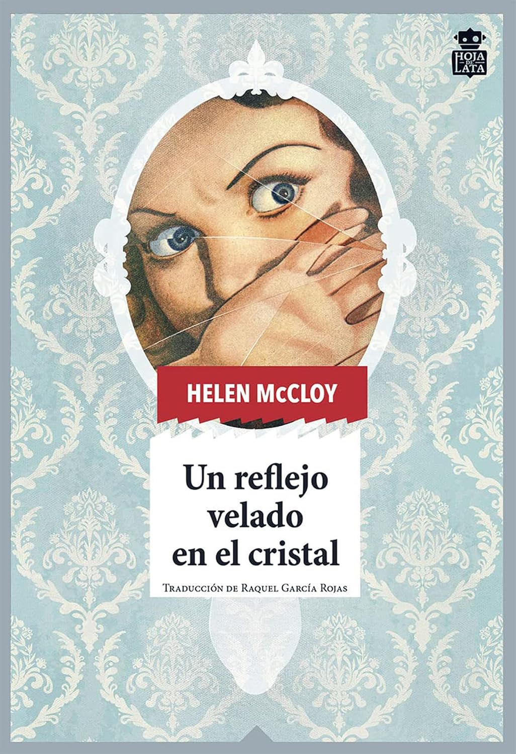 Sobre un fondo de papel pintado azul claro con motivos ornamentales blancos aparece un espejo ovalado de marco blanco. Dentro del espejo se ve el rostro fragmentado de una mujer de ojos azules y expresión de miedo, como si el cristal estuviera roto o reflejara varias imágenes superpuestas. Una de sus manos cubre parcialmente la boca. En la parte superior figura el nombre de la autora sobre una banda roja y, debajo del espejo, el título en letras negras sobre fondo blanco. En la esquina superior derecha aparece el logotipo de la editorial Hoja de Lata.